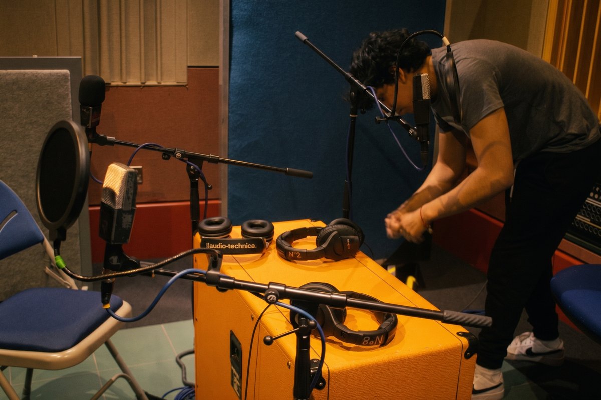 Luis placing a microphone on a guitar amp during a recording session